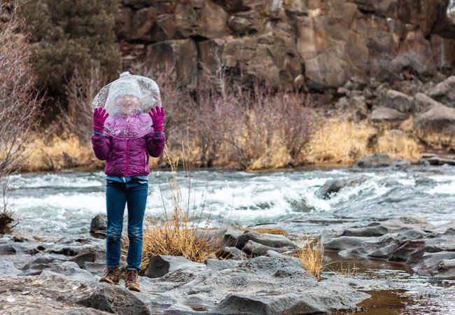 Girl stands with a giant piece of ice in a Bend park.